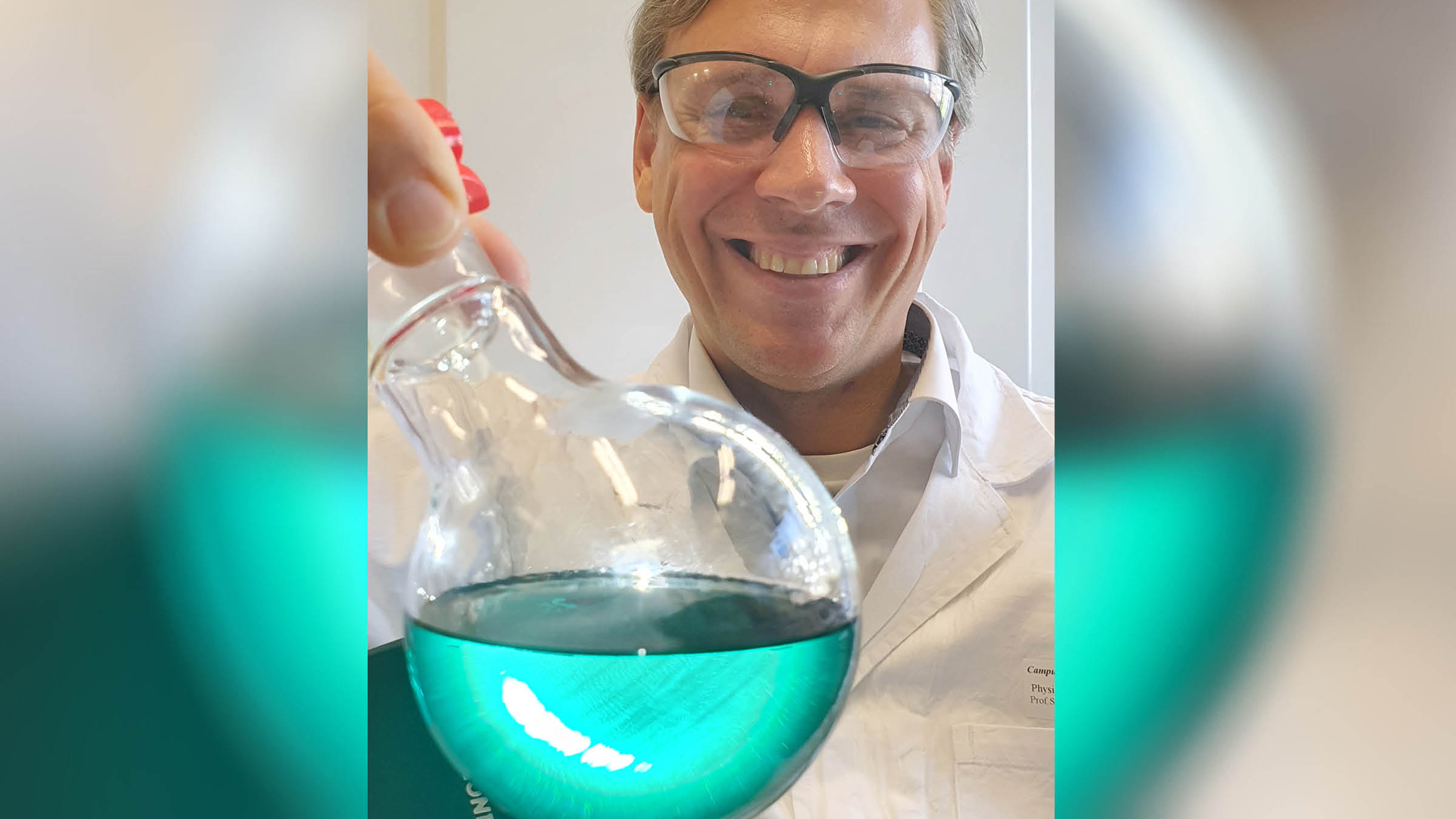 Prof. Sebastian Schlücker mit einem Glaskolben mit grüner Flüssigkeit